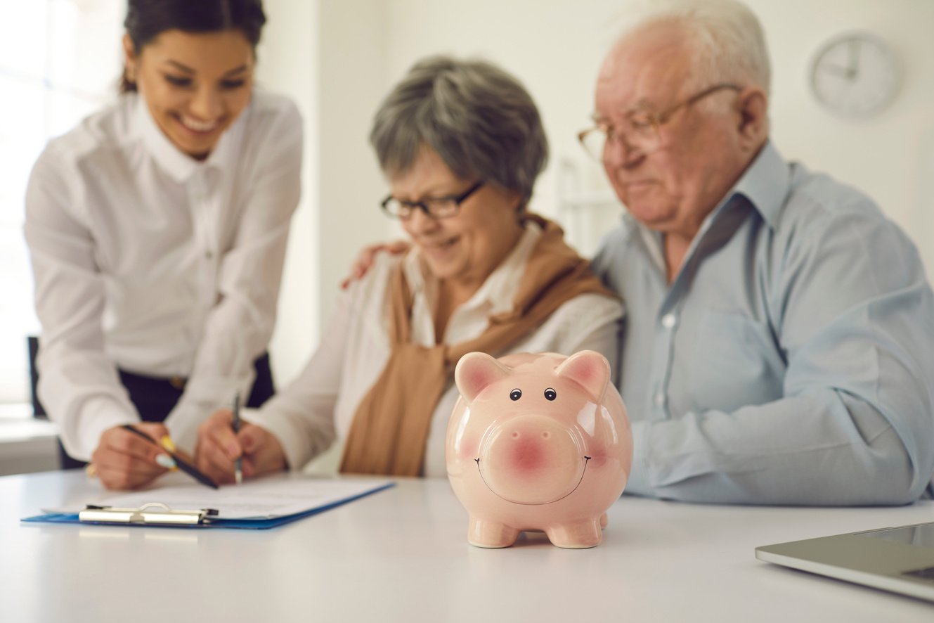 Senior Couple Sign Mortgage, Loan or Life Insurance Contract at Table in Bank Office